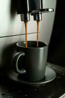 Espresso is poured into an espresso cup from a home coffee machine. photo