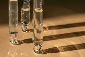 Three pipettes of cosmetic gel on a beige background. photo