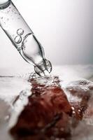 Pipette on a large piece of ice with frozen flowers. photo