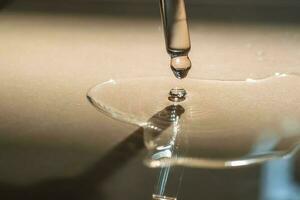 A Dripping Pipette of cosmetic gel on a beige background. photo