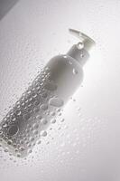 un botella de ducha gel, champú o cuerpo crema en el antecedentes de gotas. foto