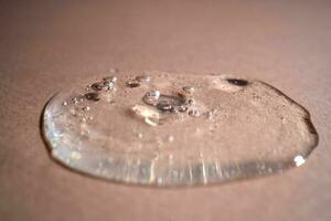A drop of serum with bubbles on a beige background. photo