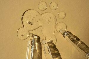 Three pipettes of cosmetic gel on a beige background. photo