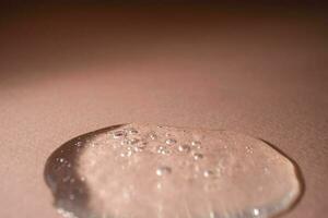 A drop of serum with bubbles on a beige background. photo