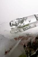 Pipette on a large piece of ice with frozen flowers. photo