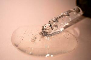 A drop of serum with bubbles on a beige background. photo