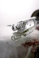 Pipette on a large piece of ice with frozen flowers. photo