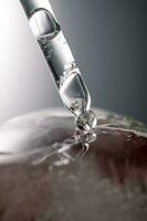 Pipette on a large piece of ice with frozen flowers. photo