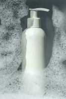 A bottle of gel or shampoo on a background of white foam. photo