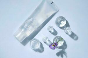 Transparent bottle of cosmetic gel on a blue background with small bottles of water. photo