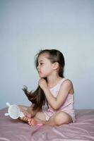 The girl is sitting on the bed and combing her long hair. photo