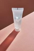 Transparent bottle of cosmetic gel on a peach background. photo