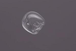 Drop of cosmetic transparent gel on a grey background. The texture of the serum, heir gel or hyaluronic booster. photo