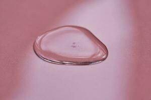 A drop of cosmetics or perfume on a pink background. photo