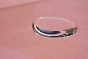 A drop of cosmetics or perfume on a pink background. photo