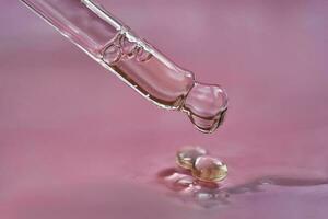 Dropper with serum or cosmetic oil on a pink background. photo