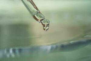 Dropper with serum or cosmetic oil on a green background. photo