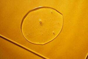 A drop of body gel or shampoo on a yellow saturated background. Texture. photo