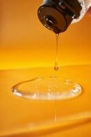 A drop of body gel or shampoo pouring from above on a yellow saturated background. photo