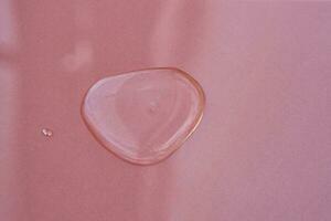 A drop of cosmetics or perfume on a pink background. photo