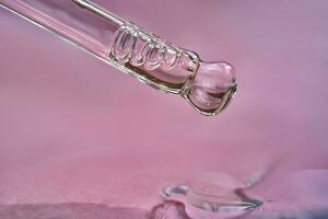 Dropper with serum or cosmetic oil on a pink background. photo