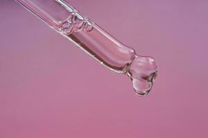 Dropper with serum or cosmetic oil on a pink background. photo