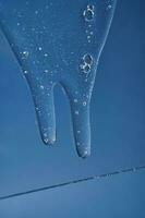 The texture of a gel or shampoo flowing down on a blue background. photo