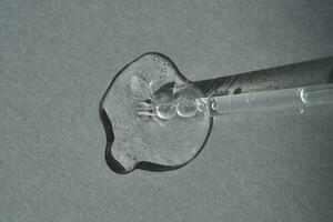 Pipette with spilled cosmetic oil or serum on a gray background. photo