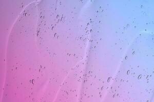 The texture of a cosmetic gel with bubbles on the background of a gradient from pink to blue. photo