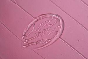 el textura de el cosmético gel en un rosado antecedentes. foto