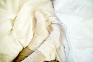 Legs in warm leggings and wool socks peek out from under the blanket. photo