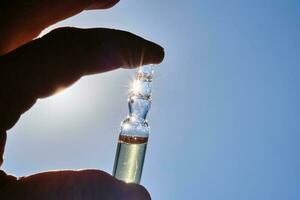 Ampoule in hand against the blue sky. photo