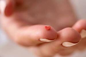 Red heart on the finger of a woman's hand. Concept. photo