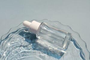 A bottle of serum in water on a blue background. photo