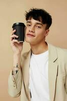 portrait of a young man black disposable glass in the hands of posing fashion light background unaltered photo