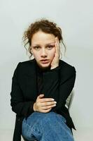 cheerful woman sitting on a chair in a black jacket fashion posing light background unaltered photo