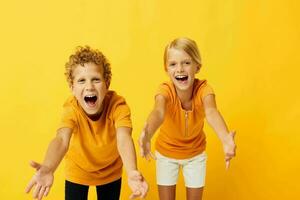 Small children in yellow t-shirts standing side by side childhood emotions isolated background unaltered photo