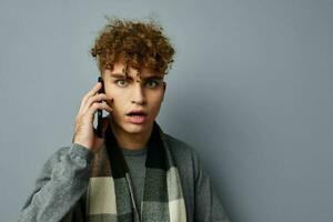 handsome guy in a plaid scarf talking on the phone posing emotions light background photo