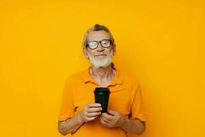 Photo of retired old man in a yellow T-shirt a glass with a drink isolated background