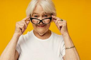 smiling elderly woman vision problems with glasses yellow background photo