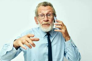 Portrait elderly man in a shirt with a tie talking on the phone light background photo