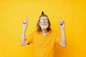 Senior grey-haired man wearing glasses green cap on his head holiday emotions yellow background photo