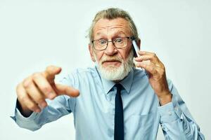 old man with the phone shows to the camera in the studio on a white background photo