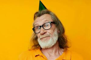 Portrait of happy senior man in a yellow t-shirt with a cap on his head fun yellow background photo