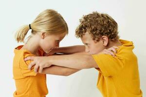 Cute stylish kids in yellow t-shirts standing side by side childhood emotions light background unaltered photo