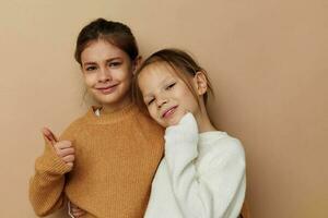 dos gracioso pequeño muchachas en suéteres posando infancia foto