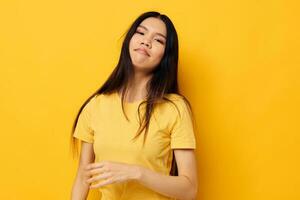 pretty brunette in a yellow t-shirt holding his head discontent yellow background unaltered photo
