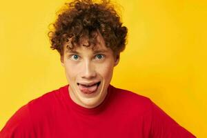 Young curly-haired man red t shirt fun posing casual wear yellow background unaltered photo