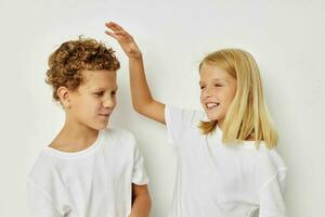 pequeño chico y niña en blanco camisetas son en pie siguiente a aislado antecedentes foto