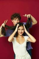 a guy stands behind a girl and holds her hair red background photo